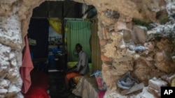 Mario Luis Poll sits for a photo on his bed behind a broken wall inside a partially destroyed mansion where he lives with five other families in Havana, Cuba, Oct. 5, 2023.