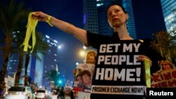 A woman holds a sign and yellow ribbons during a demonstration by family members and supporters of hostages who are being held in Gaza by Hamas gunmen, in Tel Aviv, Israel, Oct. 28, 2023.