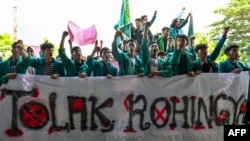 Mahasiswa memegang spanduk bertuliskan “Tolak Rohingya” saat berdemonstrasi menentang kedatangan pengungsi Rohingya di depan Dewan Perwakilan Rakyat (DPR) di Banda Aceh pada 27 Desember 2023. (CHAIDEER MAHYUDDIN / AFP)