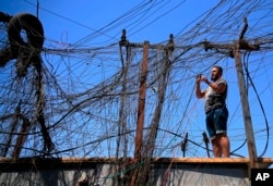 FILE - Muqtada Haider turns the switches to transfer electricity to private homes in Baghdad, Iraq, Sept. 10, 2021.