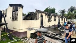 In this photo provided by Guyana's Department of Public Information, the dormitory of a secondary school is burned in Mahdia, Guyana, Monday, May 22, 2023. 