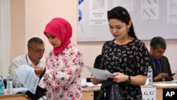 Two women hold their ballots at a polling station during a referendum in Tashkent, Uzbekistan, April 30, 2023.