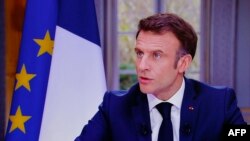 Presiden Prancis Emmanuel Macron terlihat di layar televisi selama wawancara dari Istana Elysee, di Paris, 22 Maret 2023.