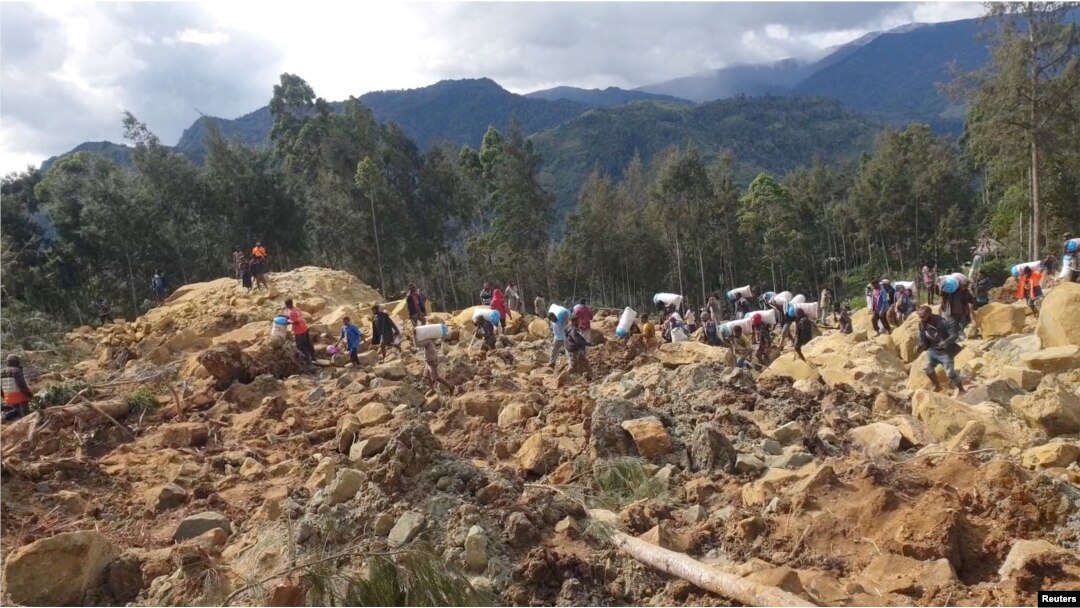 Orang-orang membawa barang-barang mereka pasca bencana tanah longsor di Provinsi Enga, Papua Nugini, 24 Mei 2024, dalam gambar diam yang diperoleh dari sebuah video. (Andrew Ruing/Handout via REUTERS)