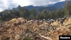 Orang-orang membawa barang-barang mereka pasca bencana tanah longsor di Provinsi Enga, Papua Nugini, 24 Mei 2024, dalam gambar diam yang diperoleh dari sebuah video. (Andrew Ruing/Handout via REUTERS)