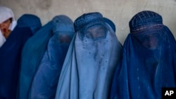 FILE - Afghan women wait to receive food rations distributed by a humanitarian aid group, in Kabul, Afghanistan, May 23, 2023.