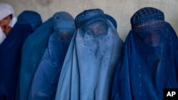 FILE - Afghan women wait to receive food rations distributed by a humanitarian aid group, in Kabul, Afghanistan, May 23, 2023. 