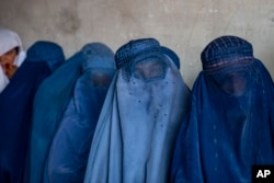 FILE - Afghan women wait to receive food rations in Kabul, Afghanistan, May 23, 2023. Afghan women are required to cover their faces and bodies in public.