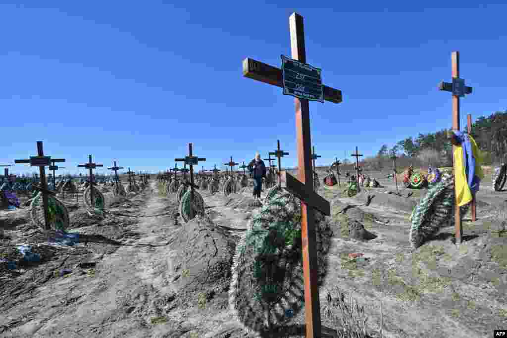 A man walks among graves of unidentified local people who were killed in the Ukrainian town of Bucha, northwest of Kyiv, a day before the celebration of the first anniversary of the Bucha liberation from Russian troops on March 31.
