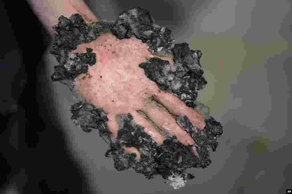 A climate activist shows his hand, covered with asphalt, after police remove is hand with hammer and chisel from a road in Berlin, Germany.