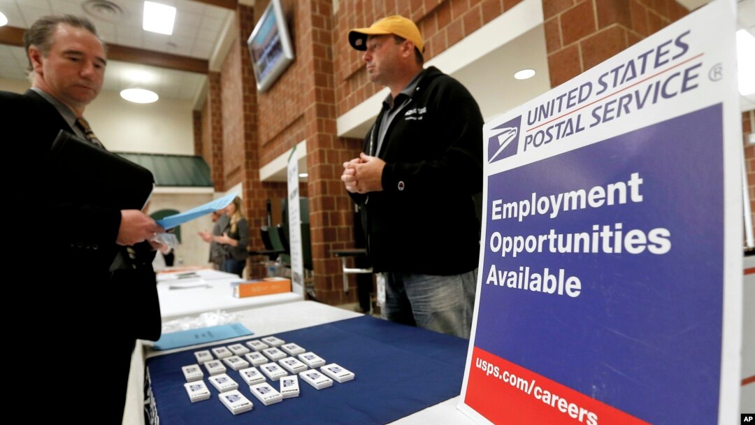 FILE - In this Nov. 2, 2017, file photo a recruiter from the postal service, right, speaks with an attendee of a job fair in the cafeteria of Deer Lakes High School in Cheswick, Pennsylvania. 