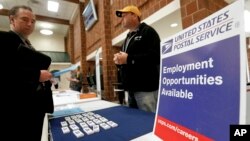 FILE - In this Nov. 2, 2017, file photo a recruiter from the postal service, right, speaks with an attendee of a job fair in the cafeteria of Deer Lakes High School in Cheswick, Pennsylvania. 