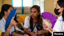 Grade 12 students use a portable electric fan and hand fans inside a classroom at the Commonwealth High School, in Quezon City, Metro Manila, Philippines, April 18, 2024.