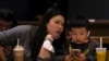 资料照 - 2023年1月19日北京一座咖啡馆里，一位母亲正在和她孩子说话，而儿子却目不转睛地玩着手上的智能手机。