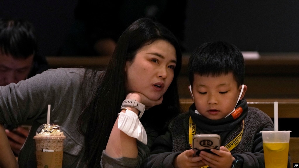 资料照 - 2023年1月19日北京一座咖啡馆里，一位母亲正在和她孩子说话，而儿子却目不转睛地玩着手上的智能手机。(photo:VOA)