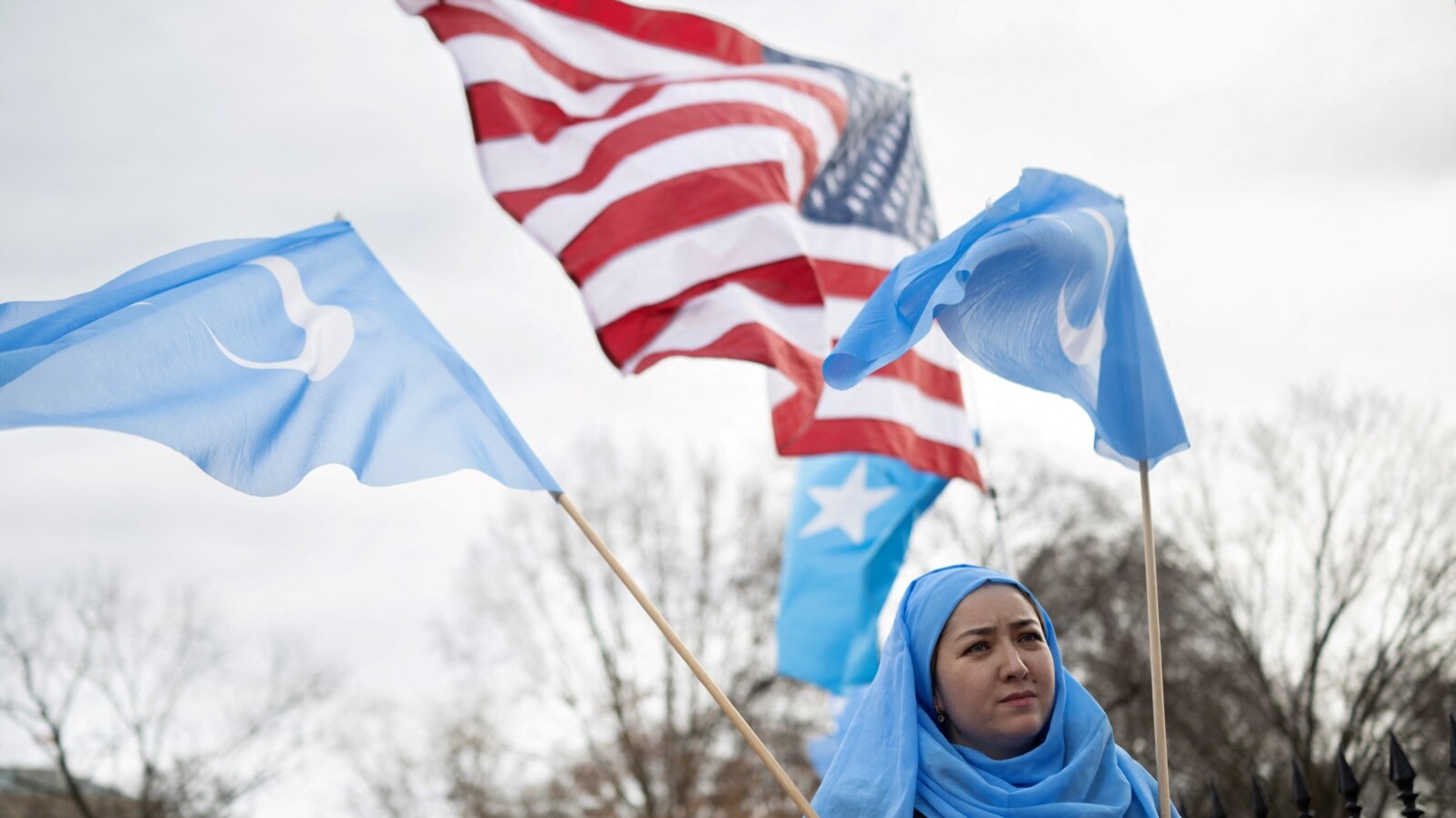 FILE - People hold up flags and signs during a protest in Washington on Feb. 5, 2023, marking the 26th anniversary of the 1997 Ghulja massacre in Ghulja City, in the Xinjiang province of China. More than 100 Uyghur died in the incident.