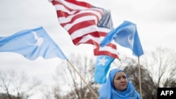 FILE - People hold up flags and signs during a protest in Washington on Feb. 5, 2023, marking the 26th anniversary of the 1997 Ghulja massacre in Ghulja City, in the Xinjiang province of China. More than 100 Uyghur died in the incident.