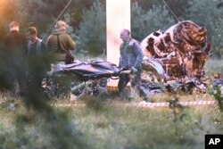 People carry a body bag away from the wreckage of a crashed private jet, near the village of Kuzhenkino, Tver region, Russia, Aug. 24, 2023.