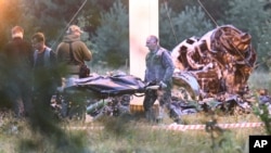 People carry a body bag away from the wreckage of a crashed private jet, near the village of Kuzhenkino, Tver region, Russia, Aug. 24, 2023.