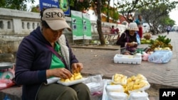 FILE - Women prepare jackfruit for sale along a street in Luang Prabang, Laos, Jan. 31, 2024.