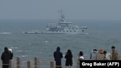 Kapal tunda milik Angkatan Laut Tentara Rakyat China (PLA) berlayar di Selat Taiwan melewati para turis yang mengunjungi Pulau Pingtan di Provinsi Fujian, yang paling dekat dengan Taiwan, 7 April 2023. (Foto: Greg Baker/AFP)