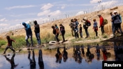 Migrants seeking asylum cross the Rio Bravo river to return to Mexico from the United States, after members of the Texas Army National Guard extend razor wire to inhibit migrants from crossing, as seen from Ciudad Juarez, Mexico, May 13, 2023. 