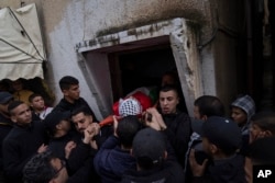 Mourners carry the body of Montaser Shawwa, 16, out of the family house, during his funeral in the West Bank refugee camp of Balata, Nablus, Tuesday, Feb. 21, 2023.