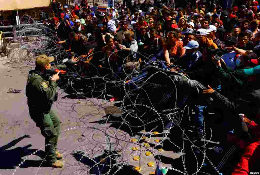 Migrants mostly from Venezuela try to cross a barrier as they take part in a protest at the Paso del Norte international bridge to request asylum in the United States, seen from Ciudad Juarez, Mexico, March 12, 2023.