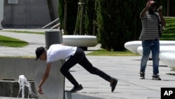 A man reaches to touch water in a fountain amid hot weather at Eleftherias square in central Nicosia, Cyprus, June 14, 2024.