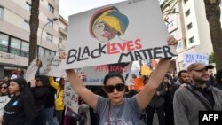 FILE: Protesters lift placards during a demonstration in Tunis on February 25, 2023, against controversial remarks by the Tunisian President regarding illegal migrants that critics said were openly racist.