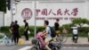 北京街头人们路过中国人民大学校园外墙的标识。（2024年7月22日）