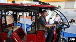 FILE - An exhibitor sits inside an E-rickshaw on display during the Hyderabad E-Motor Show at Hitex Exhibition Centre in Hyderabad, Feb. 8, 2023. 