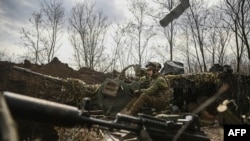 An Ukrainian serviceman sits on an anti-air gun near Bakhmut, on March 24, 2023. 