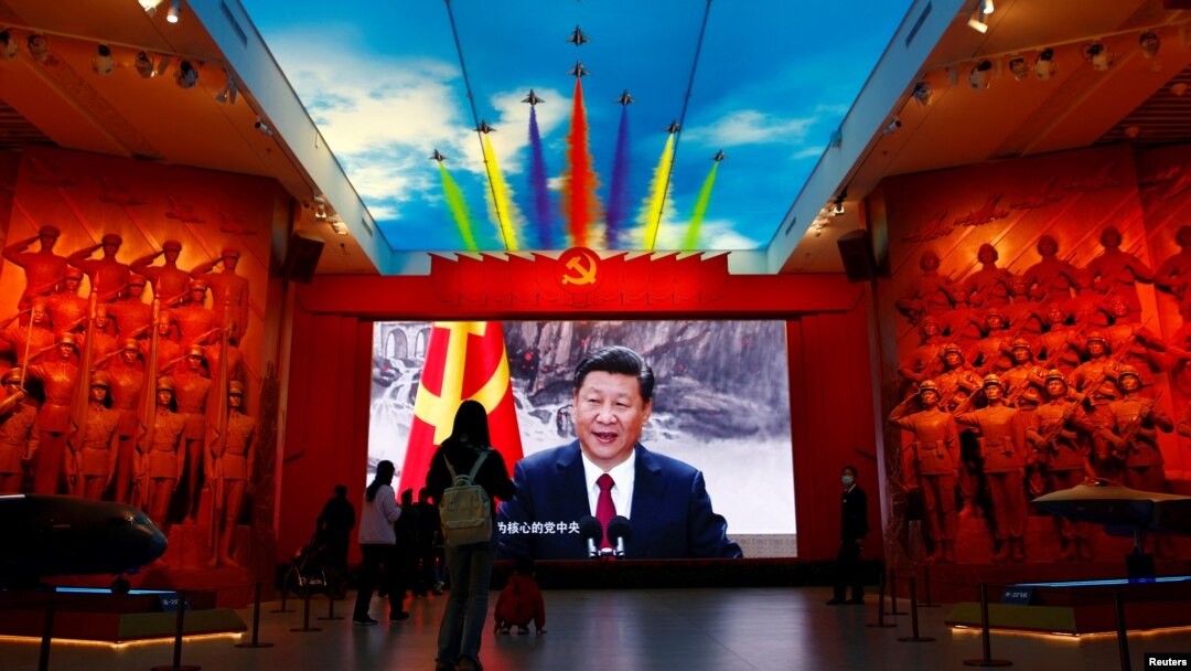 Pengunjung berdiri di depan layar raksasa yang menampilkan Presiden China Xi Jinping di samping bendera Partai Komunis China, di Museum Militer Revolusi Rakyat China di Beijing, China 8 Oktober 2022. (Foto: REUTERS/Florence Lo)