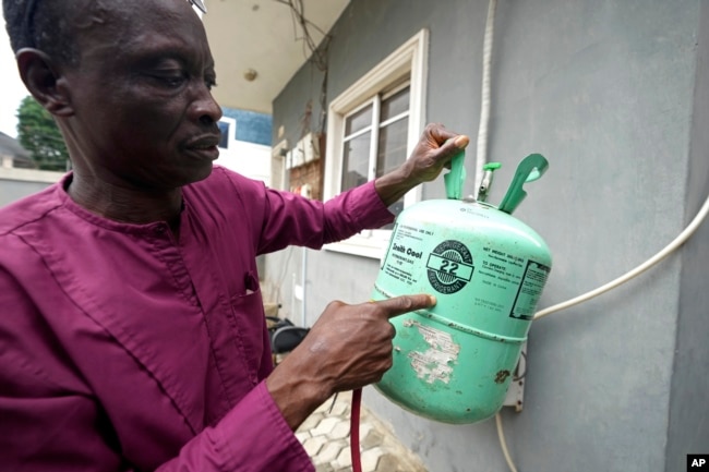 A technician points at an R-22 refrigerant for an air conditioner while working in Lagos, Nigeria, Thursday, July 18, 2024. (AP Photo/Sunday Alamba)