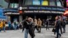 Para pejalan kaki di sekitar Times Square, New York, saat lini masa menampilkan berita tentang gempa bumi di New York, pada Jumat, 5 April 2024. (Foto: Brittainy Newman/AP Photo)