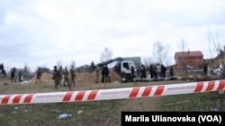 Правоохоронці працюють на місці масового поховання біля церкви Святого Апостола Андрія Первозванного та Всіх Святих у Бучі. Квітень 2022.