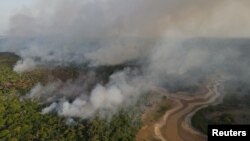 FILE - Smoke billows from a wildfire during a drought in the Amazon rainforest near a dry river in Iranduba, Amazonas state, Brazil September 25, 2023.