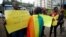 FILE - An LGBT activist walks past anti-gay rights protesters holding placards, after a ruling by Kenya's high court to upheld a law banning gay sex, outside the Milimani high Court in Nairobi, Kenya May 24, 2019. 