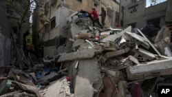 Palestinians inspect the rubble of a destroyed building that the Israeli military said targeted the house of an Islamic Jihad member in Gaza City, May 13, 2023.