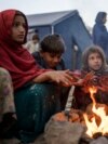 FILE - Displaced Afghan children warm themselves at a fire in a camp near the Torkham Pakistan-Afghanistan border crossing in Torkham, Afghanistan, Nov. 4, 2023, following their repatriation from Pakistan.