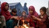 وطن واپسی پر افغان بچے پاکستان اور افغان کے درمیان سرحد طورخم پر سردی سے بچنے کے لیے آگ تاپ رہے ہیں۔ 4 نومبر 2024 