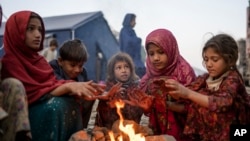 وطن واپسی پر افغان بچے پاکستان اور افغان کے درمیان سرحد طورخم پر سردی سے بچنے کے لیے آگ تاپ رہے ہیں۔ 4 نومبر 2024 