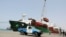 A coastguard soldier stands on a patrol vehicle while a commercial ship unloads containers in the Houthi-held Red Sea port of Hodeidah, Yemen, Feb. 25, 2023. 