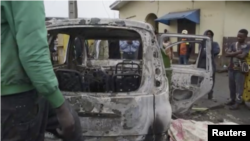 FILE - In this image taken from video, people observe the aftermath of an attack by armed militants in Cameroon's South West region on Sept. 9, 2023. The militants stopped cars, shot at passengers and set vehicles ablaze in the village of Muea, killing at least two people.