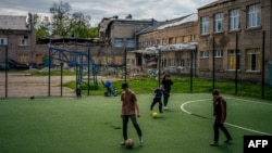 Children play football next to a damaged building after a shelling in the town of Kramatorsk, Donetsk region during the Russian invasion of Ukraine, May 6, 2023.