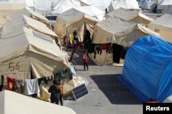 Anak-anak berdiri di luar tenda di kamp penampungan korban gempa, di pinggiran kota Jandaris yang dikuasai pemberontak, Suriah, 15 Februari 2023. (REUTERS/Khalil Ashawi)