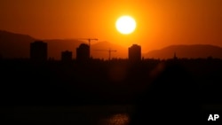 FILE - The sun sets over Seattle's University District, May 13, 2023, seen from Medina, Wash. A hazardous heat wave is expected to bring scorching temperatures to the Pacific Northwest beginning Aug. 14, according to the National Weather Service.
