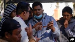 FILE: Migrants get help with the CBPOne app from a Tijuana, Mexico, city worker, Jan. 24, 2023, in Tijuana, Mexico.