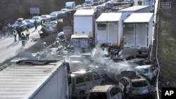 Firefighters work as vehicles smolder after several trucks and cars crashed on M1 motorway near Herceghalom, Hungary, March 11, 2023. 